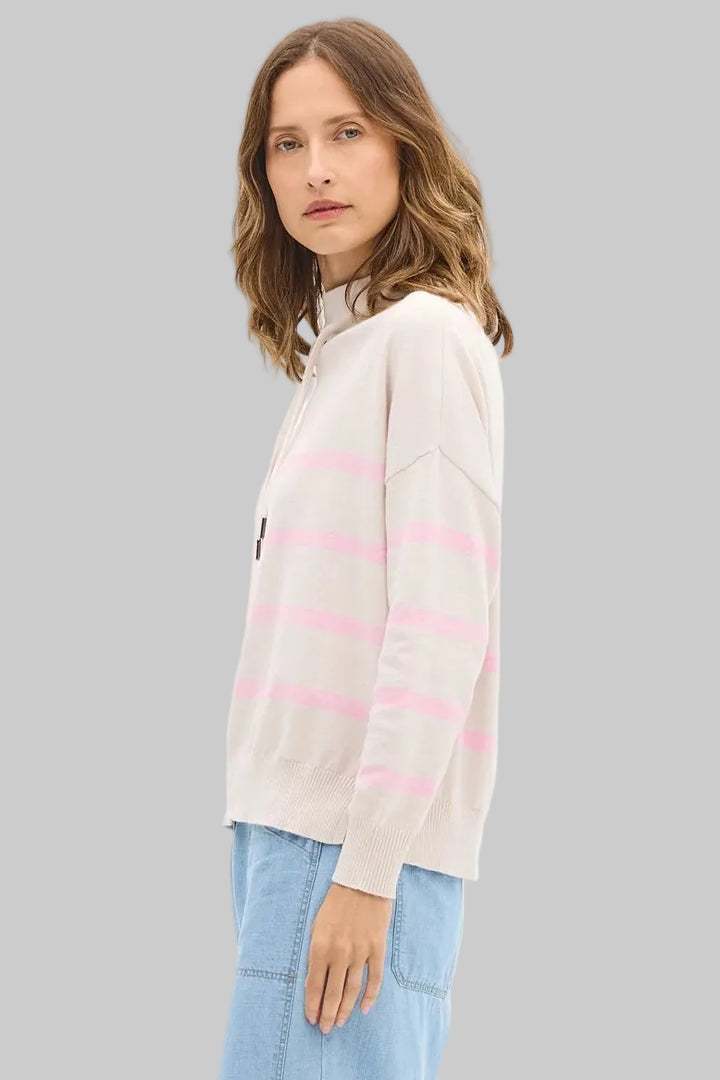 Woman wearing a striped sweater and light blue pants on a white background