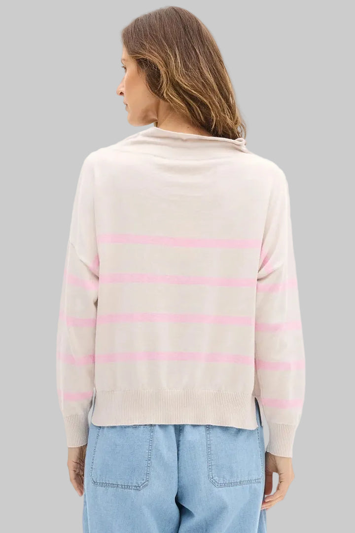 Woman wearing a light pink and beige striped sweater with blue pants on a white background