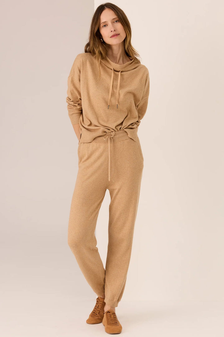 Woman wearing a beige jumpsuit on a plain background