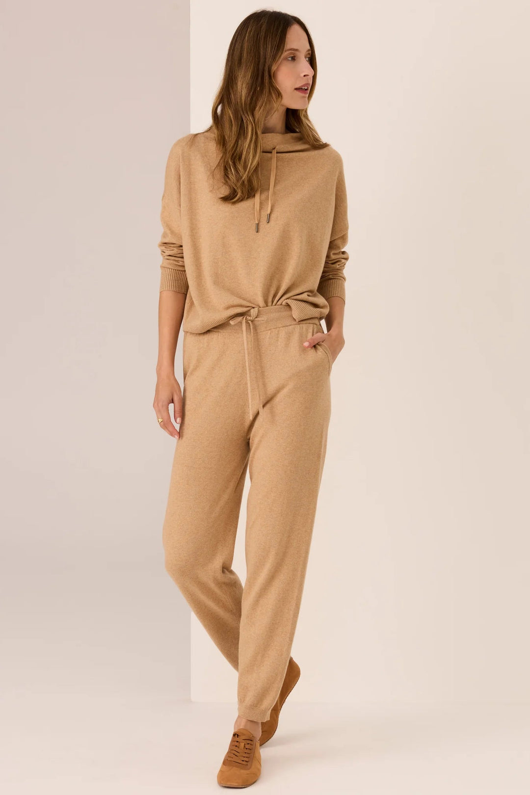 Woman wearing a beige jumpsuit on a plain background