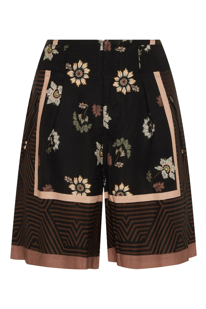 Black wide-leg shorts featuring a floral print with beige, white, and green elements, accented by tan geometric patterns and borders.