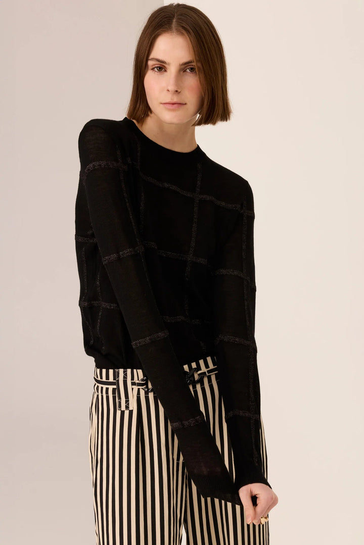 Woman wearing a black textured sweater with a beige background