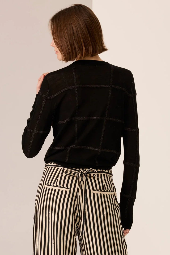 Person wearing a black jacket and striped pants on a plain background