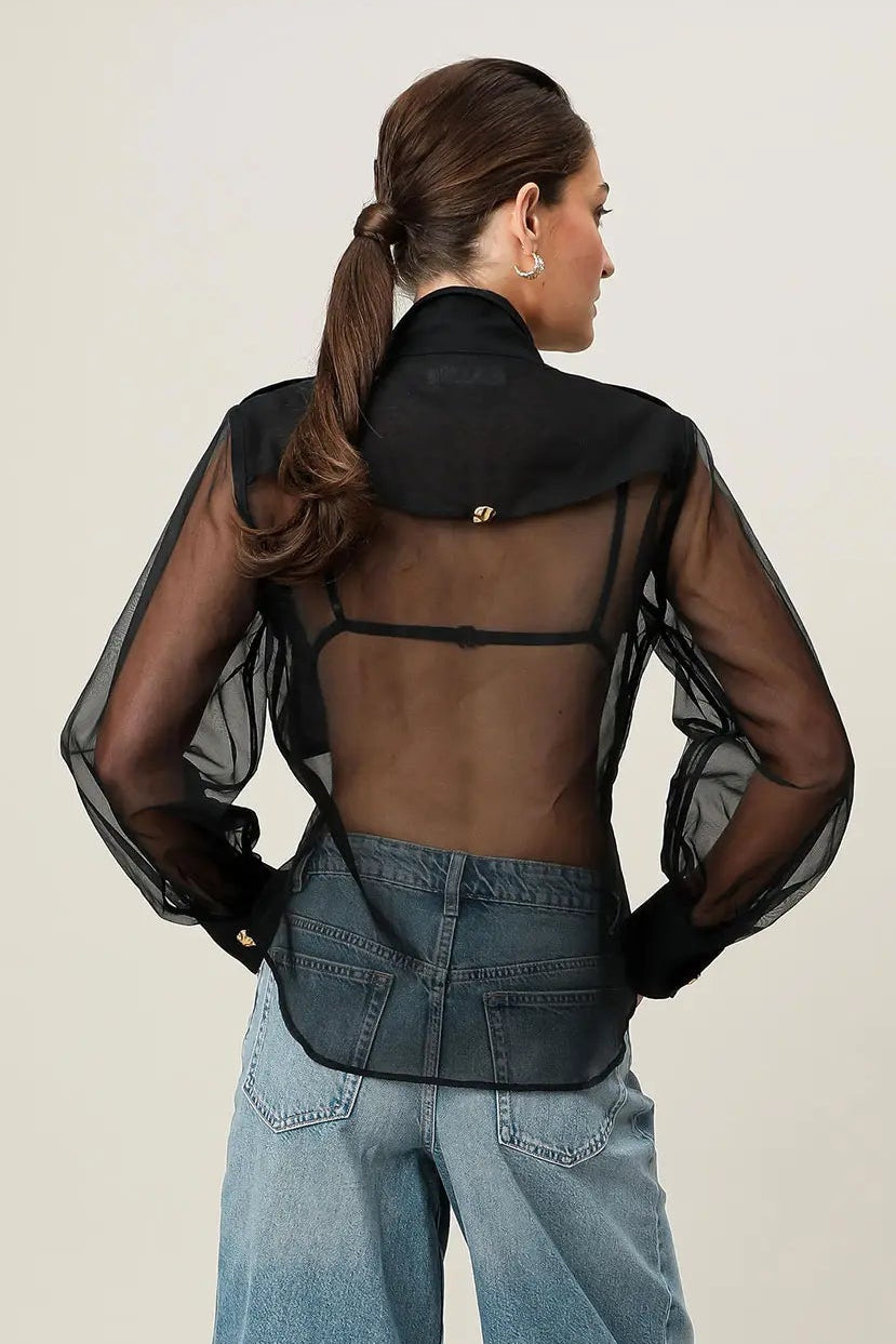 Person wearing a sheer black top and blue denim shorts on a white background