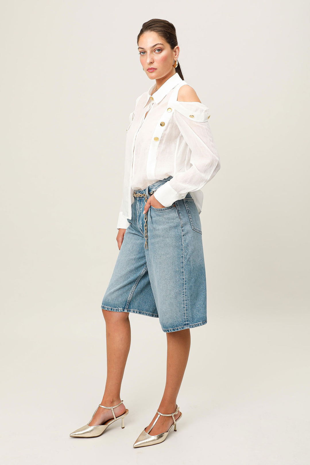 Woman wearing a white blouse and denim shorts on a plain background