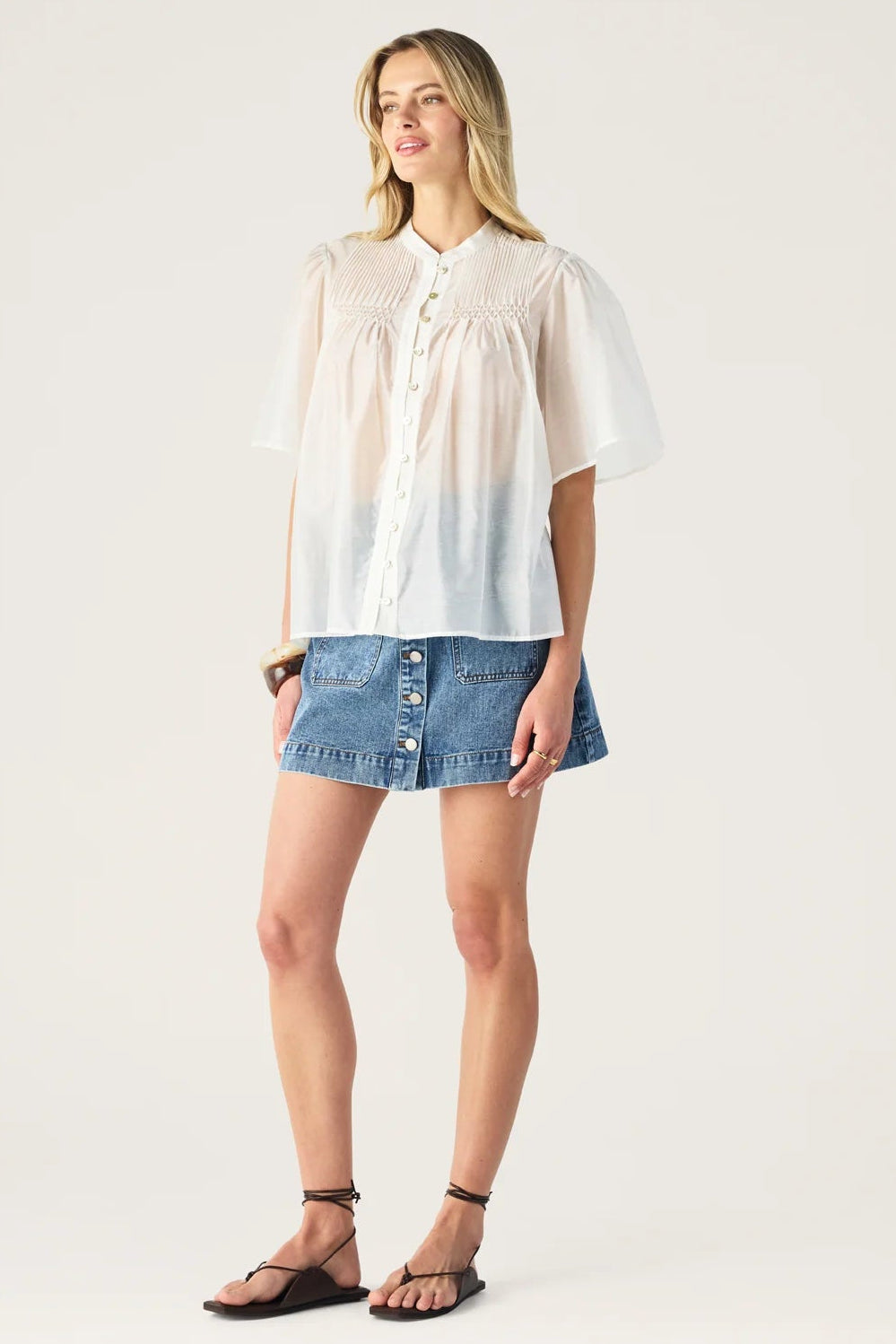 Woman wearing a white blouse with a blue denim skirt on a white background