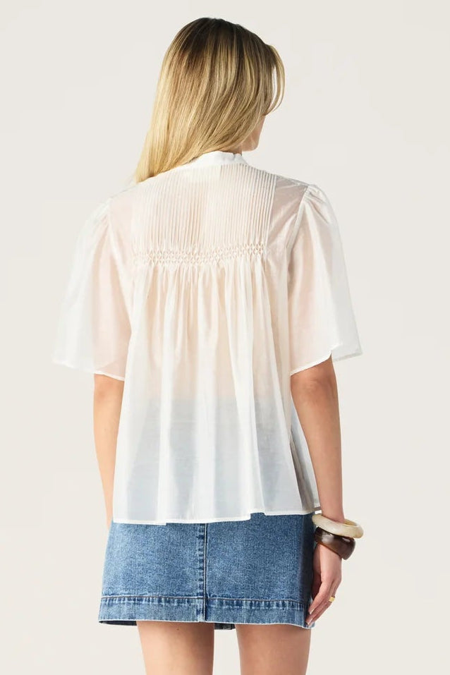 Woman wearing a white to blue gradient blouse and denim skirt on a white background