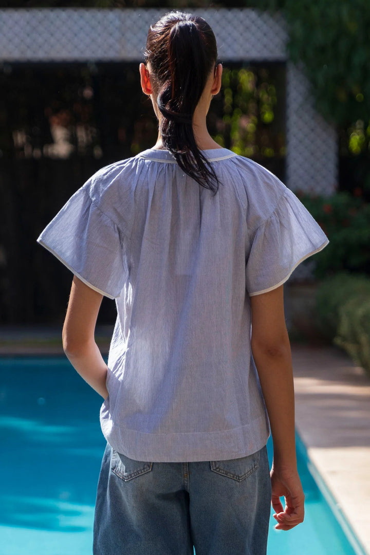 Person wearing a light blue shirt by a poolside