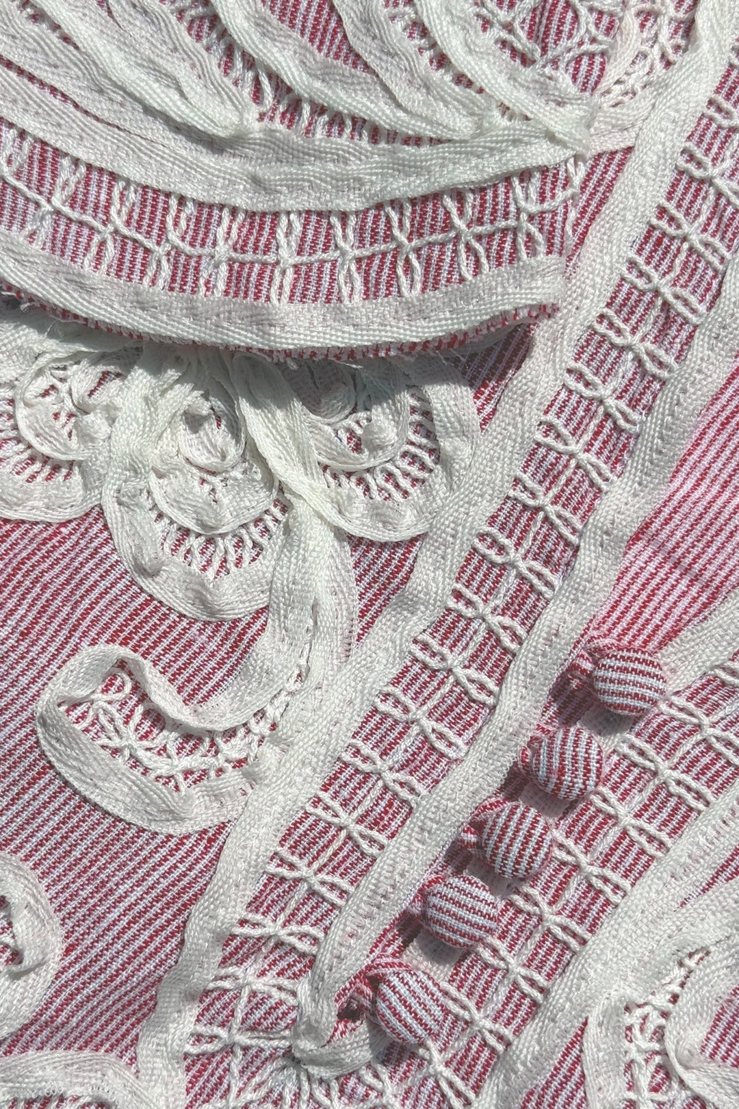Close-up of silver embroidered pattern on a pink fabric background