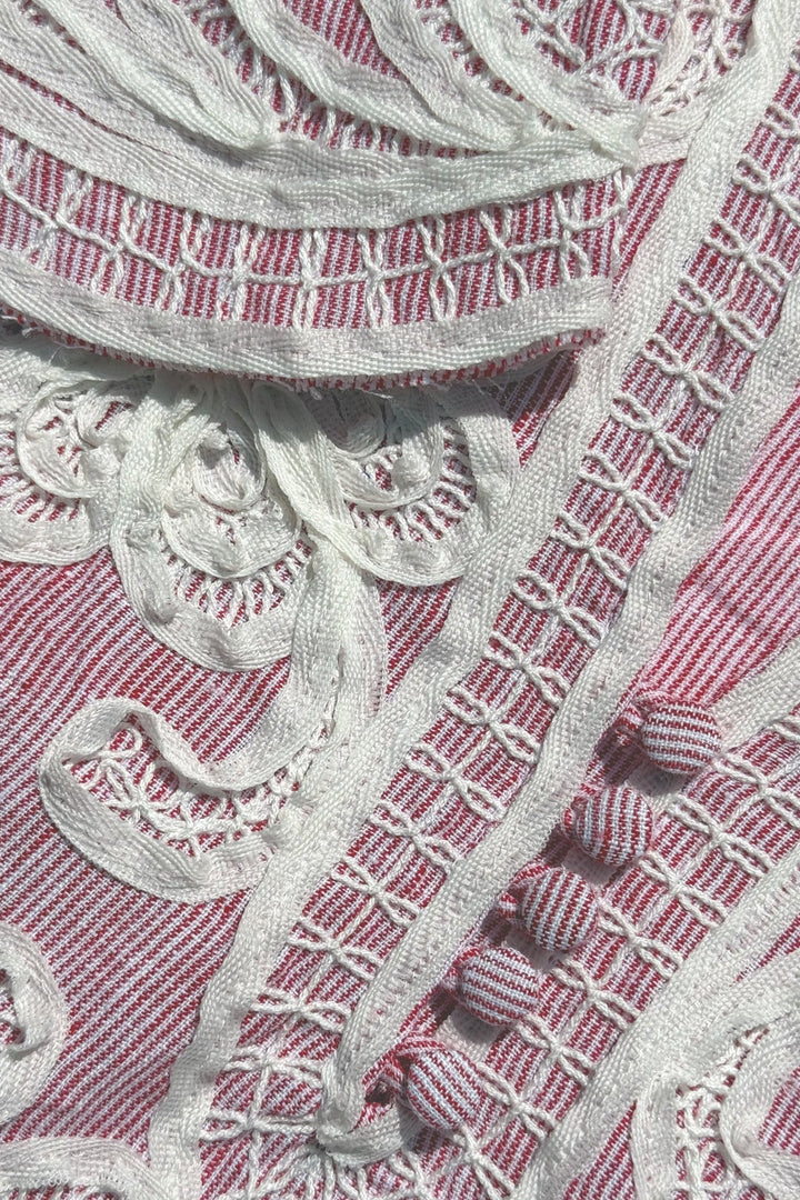 Close-up of silver embroidered pattern on a pink fabric background