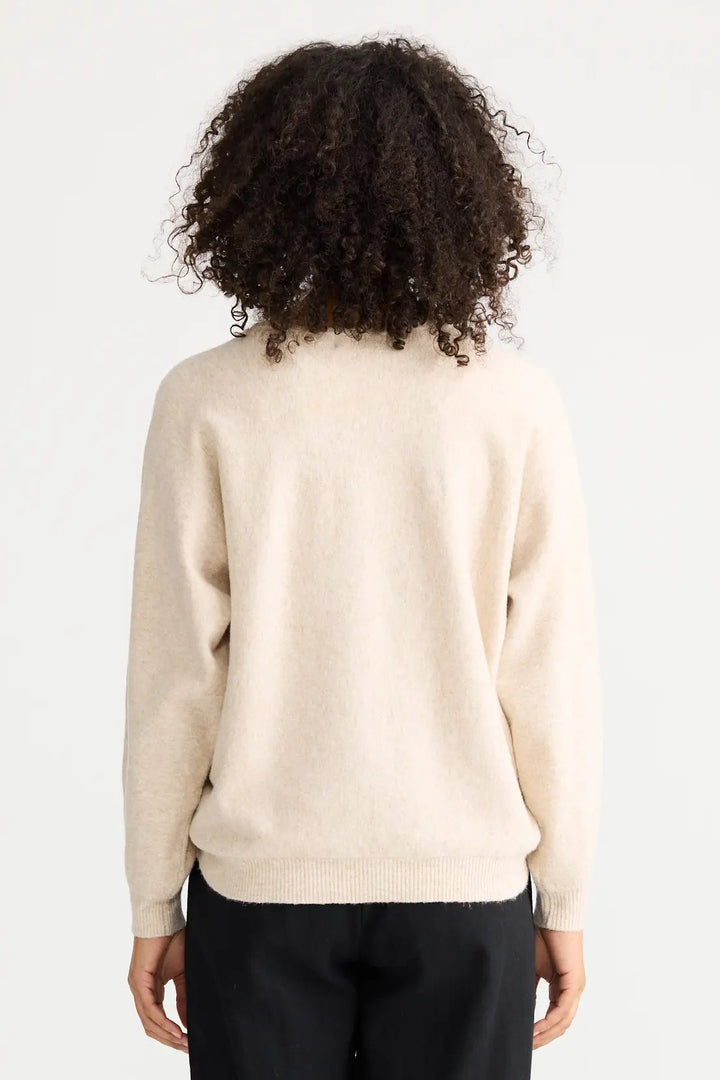 Person wearing a cream sweater and black pants on a white background