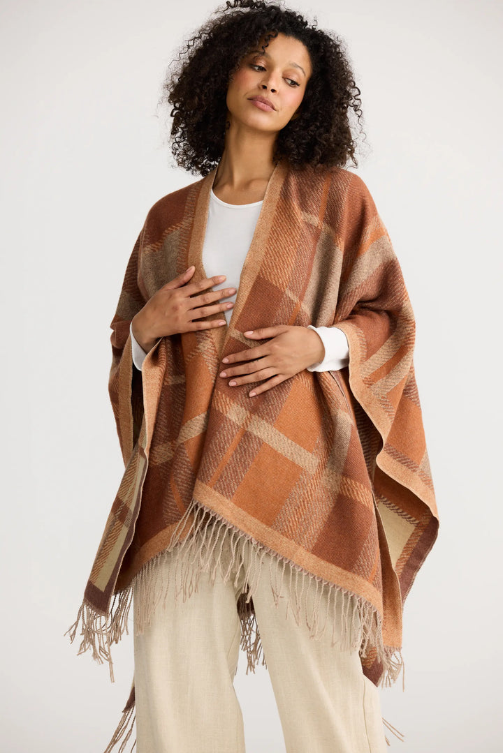 Woman wearing a brown plaid poncho on a white background