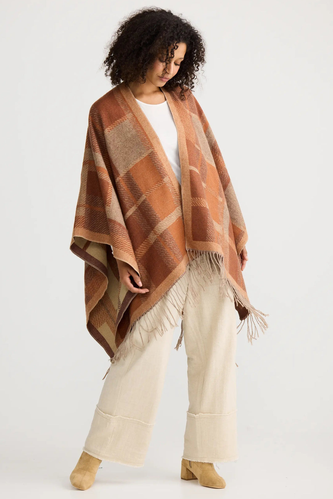 Woman wearing a brown plaid shawl over a white outfit on a white background