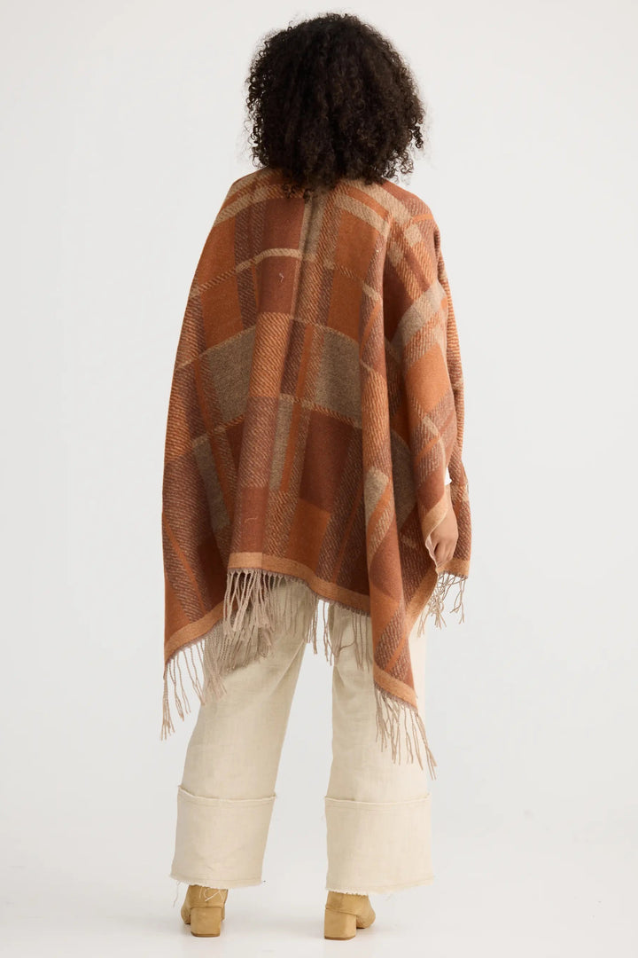 Person wearing a brown patterned poncho on a white background