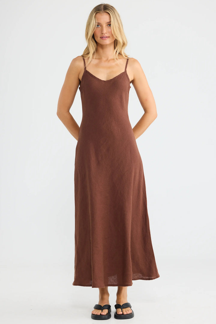 A woman modeling a brown spaghetti-strap maxi slip dress against a plain white studio background.