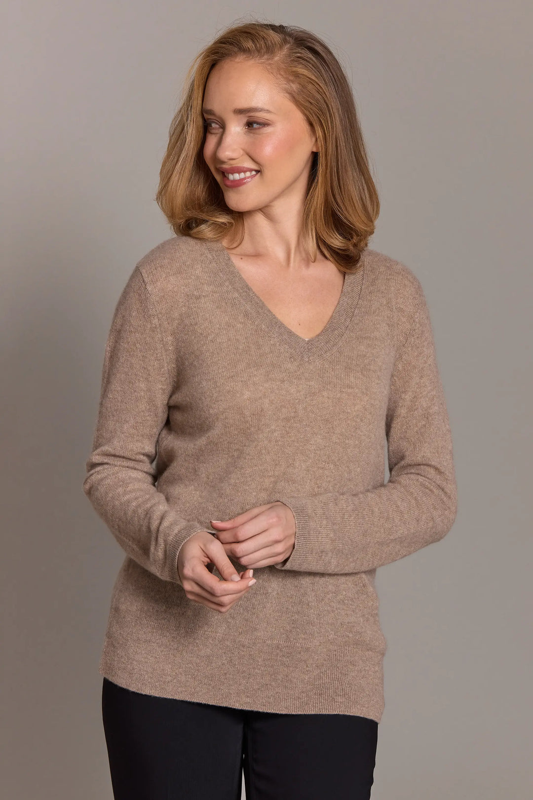 Woman wearing a beige sweater against a plain background