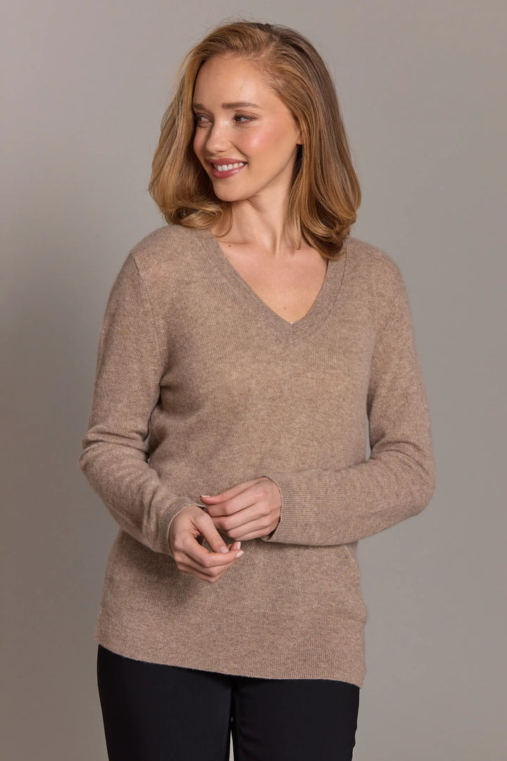 Woman wearing a beige sweater against a plain background