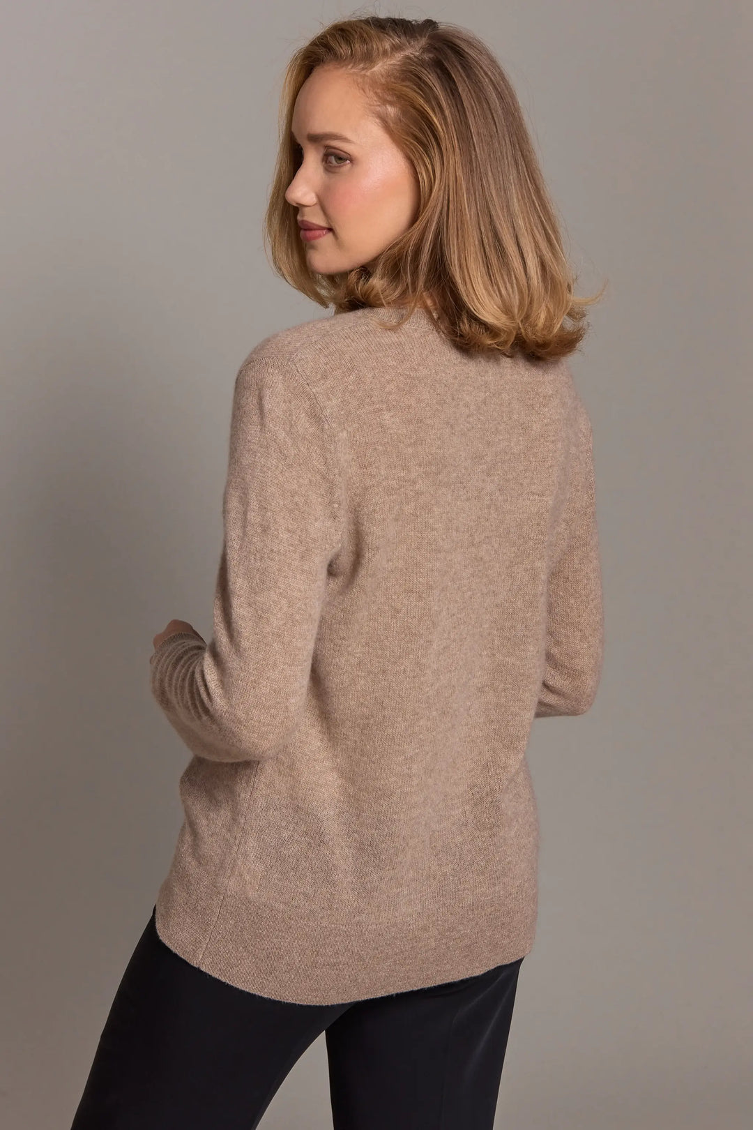 Woman wearing a beige sweater against a plain background
