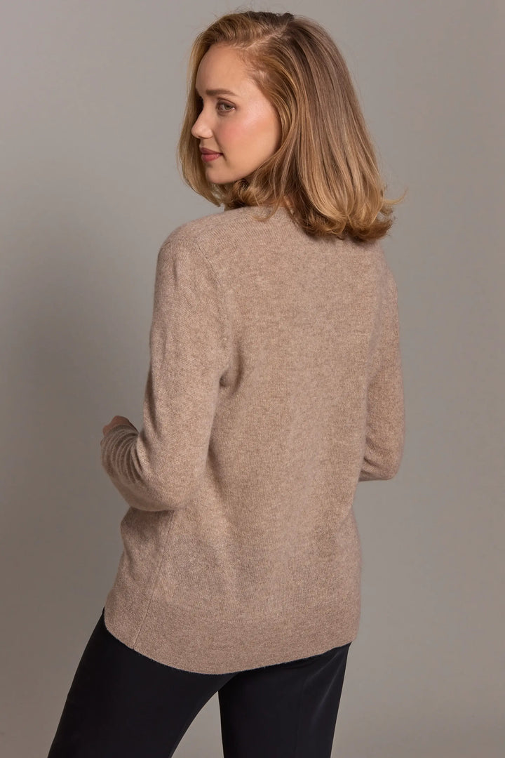 Woman wearing a beige sweater against a plain background