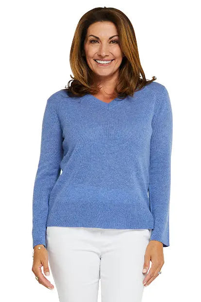 Woman wearing a blue sweater and white pants on a white background