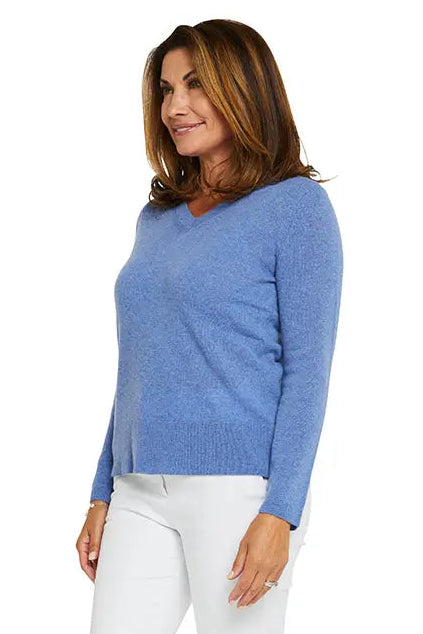 Woman wearing a blue sweater and white pants on a white background