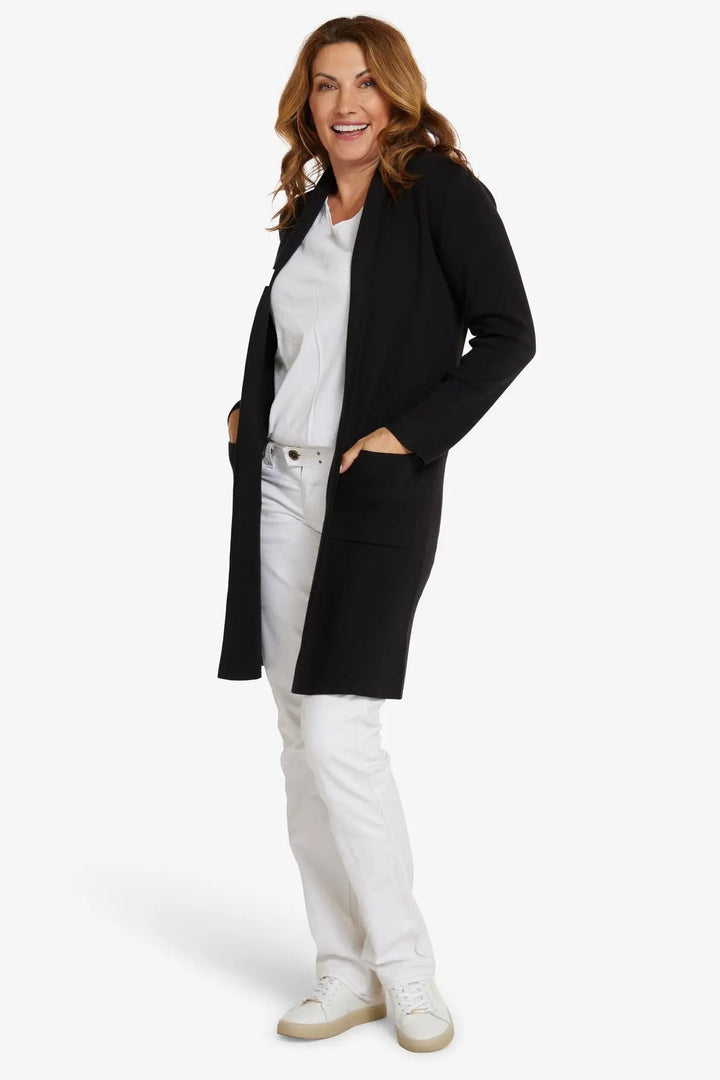 Woman wearing a black coat over a white outfit on a white background