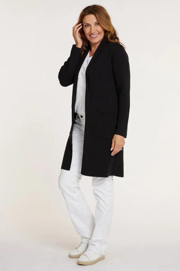 Woman wearing a black cardigan, white shirt, and pants on a white background