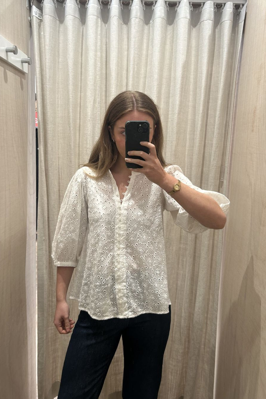 Person wearing a white blouse with black pants in a fitting room.