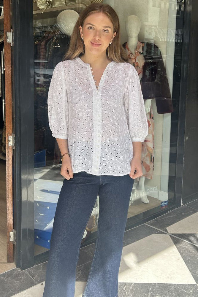 Woman standing in front of a store with mannequins and clothing displayed.