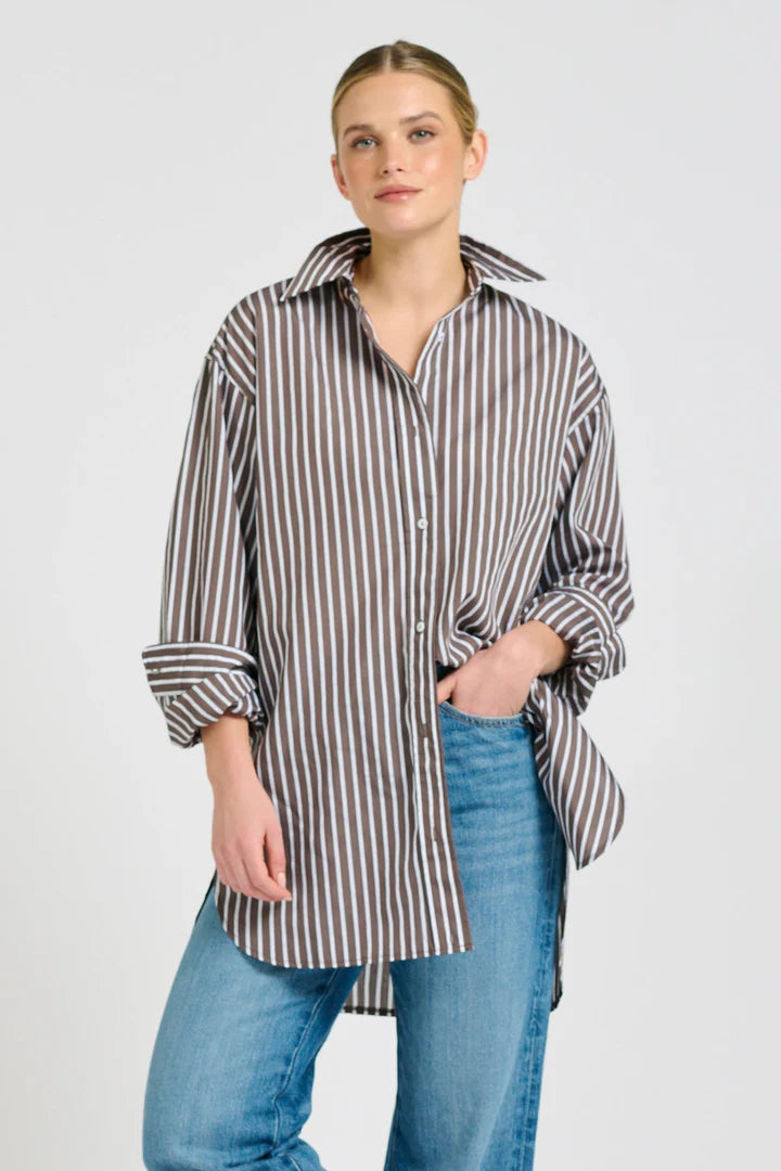 Woman wearing a striped shirt and jeans on a plain background