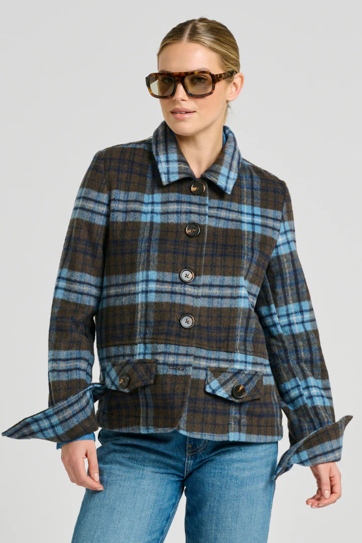 Woman wearing a plaid jacket and sunglasses on a plain background