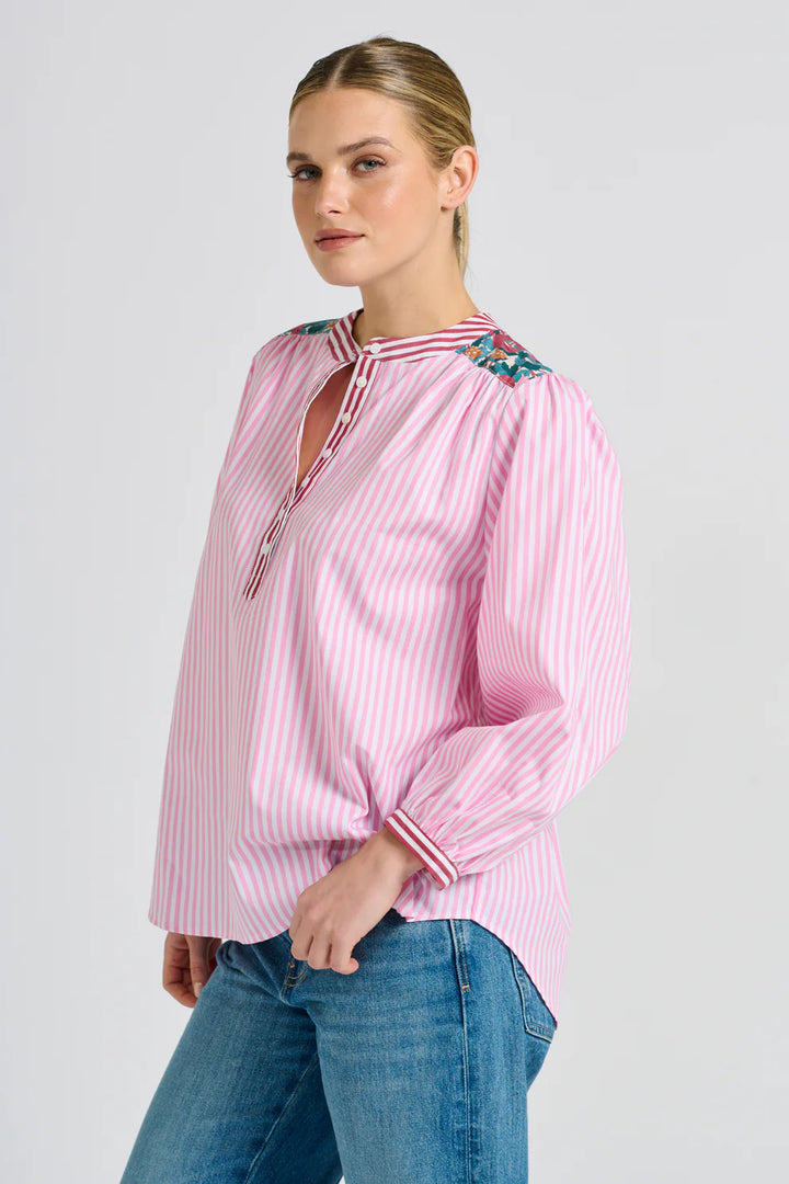 Woman wearing a pink striped blouse with floral accents on a white background
