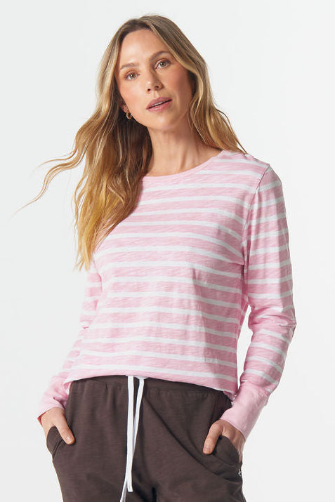 Woman wearing a pink striped sweater and brown pants on a white background