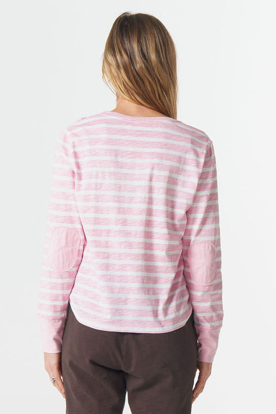 Person wearing a pink and white striped long-sleeve shirt and brown pants on a white background