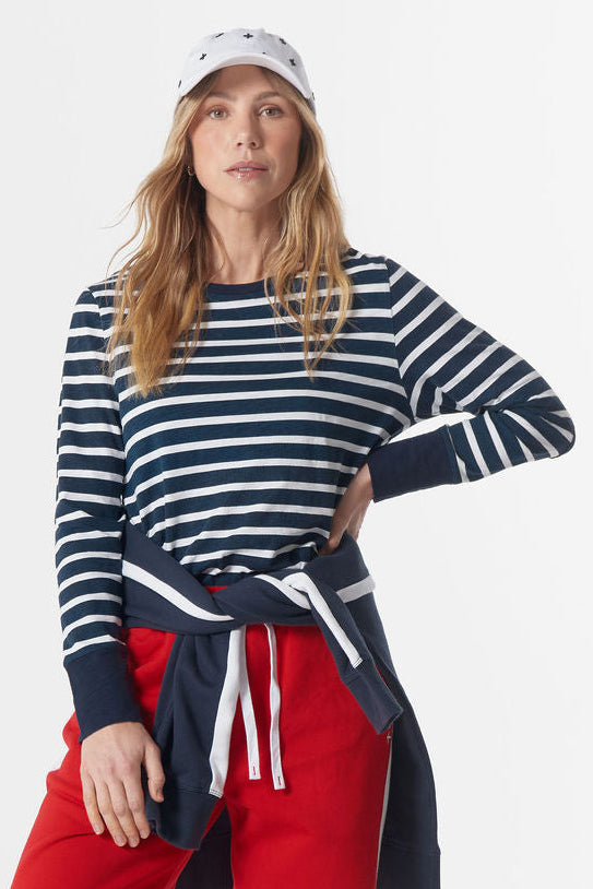 Woman wearing a striped sweater, red pants, and a cap on a white background