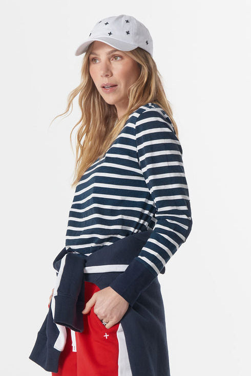 Woman wearing a striped sweater, red pants with a white stripe, and a cap on a white background