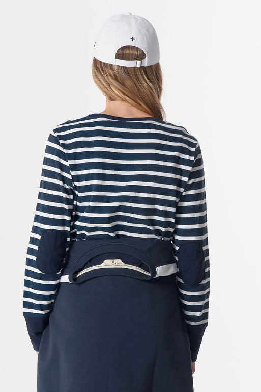 Person wearing a blue and white striped sweater, navy skirt, and red pants on a white background