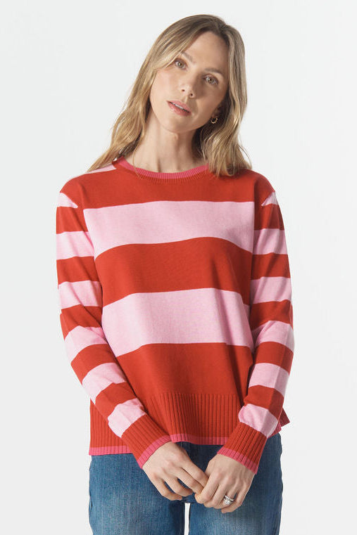 Person wearing a red and pink striped sweater with blue jeans on a white background
