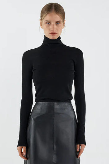 Person wearing a black turtleneck and leather skirt on a white background