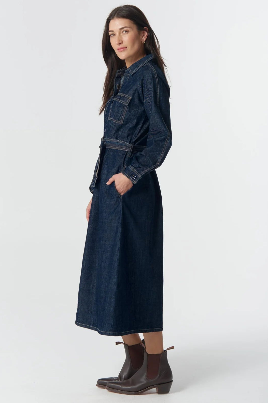 Woman wearing a long denim dress on a white background
