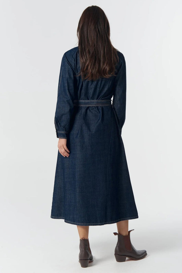 Woman wearing a long dark blue dress with a belt on a white background