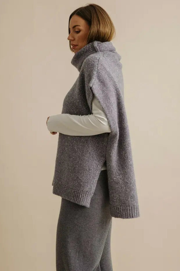 Woman wearing a gray knitted vest over a white shirt on a beige background