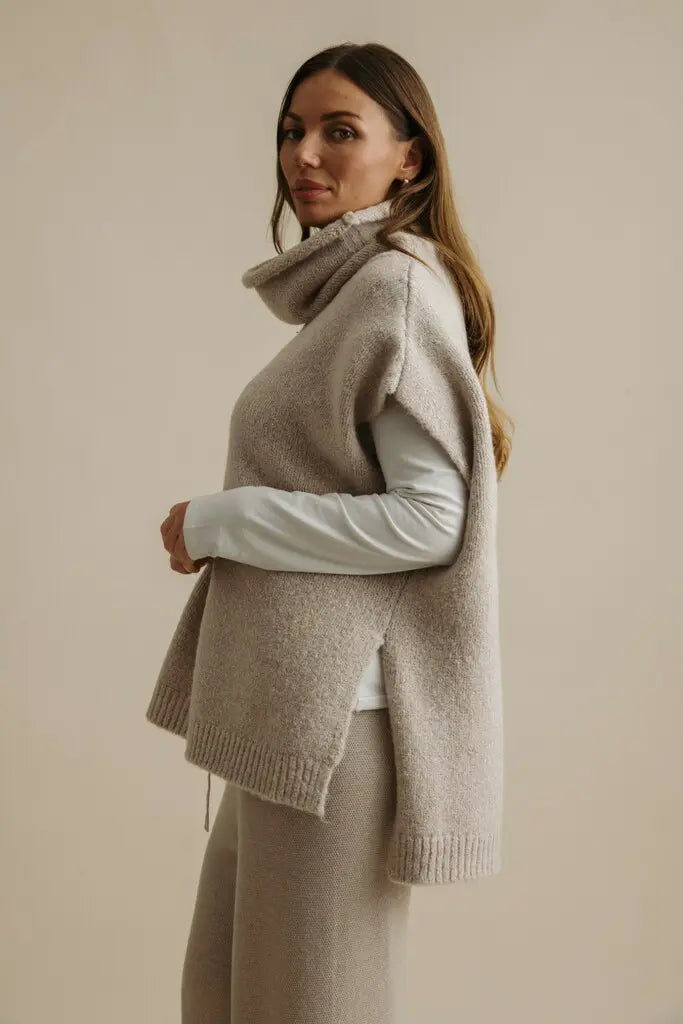 Woman wearing a beige sweater over a light shirt on a beige background