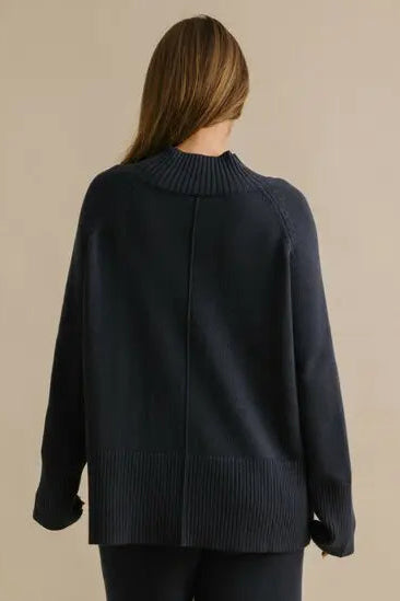 Person wearing a dark blue outfit on a beige background