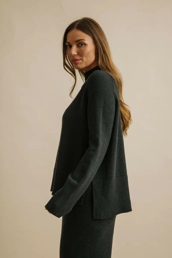 Woman wearing a dark green sweater against a beige background