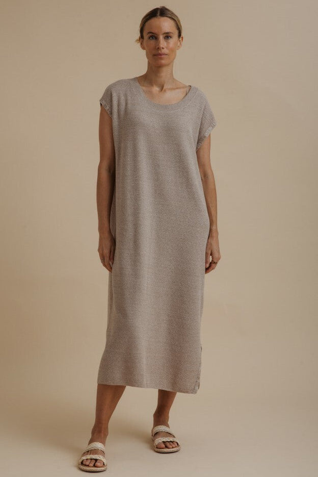Woman wearing a plain beige dress against a neutral background