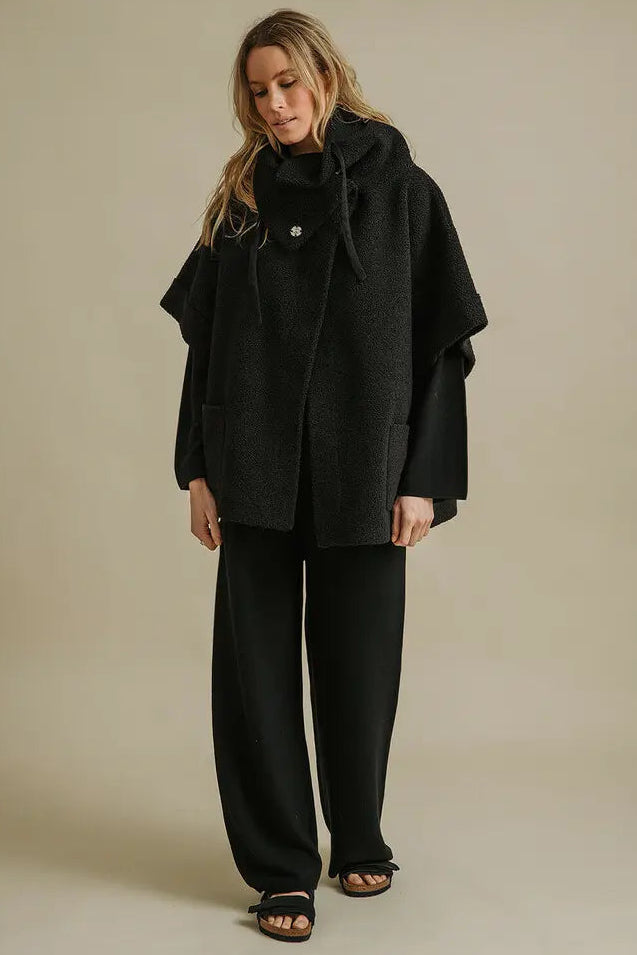 Woman wearing a black outfit against a beige background