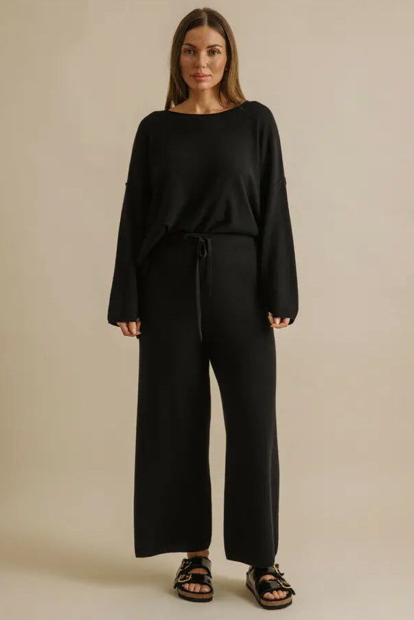 Woman wearing a black outfit on a beige background