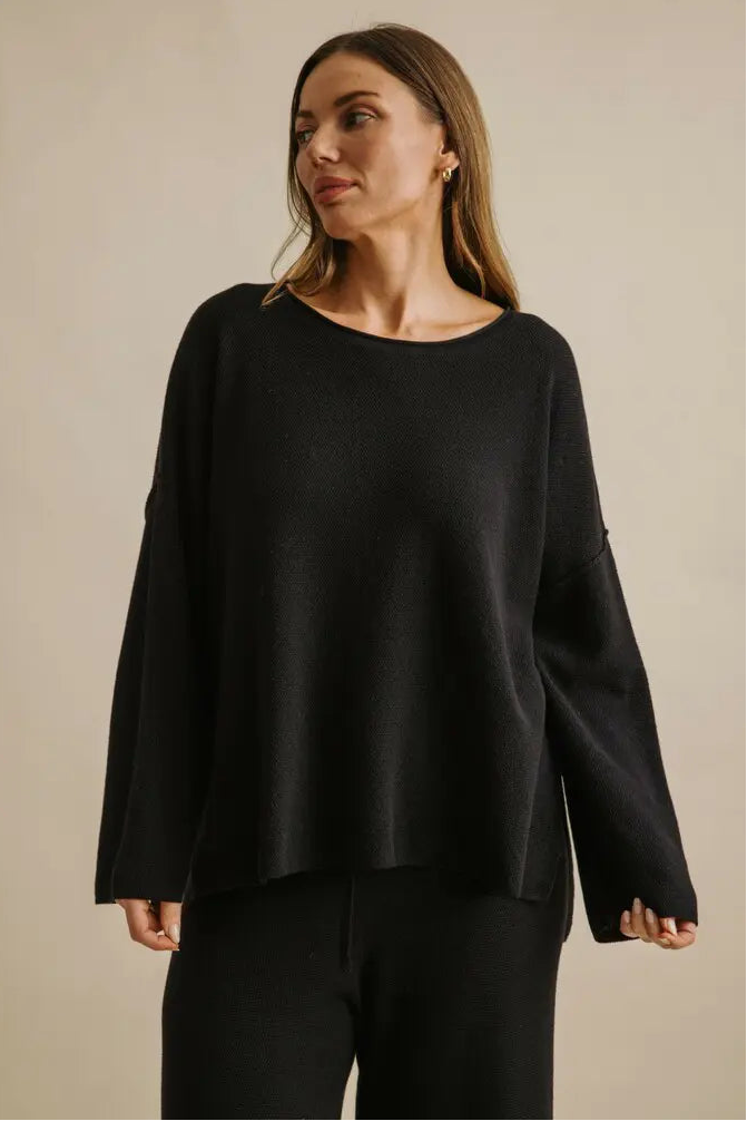 Woman wearing a black sweater against a beige background