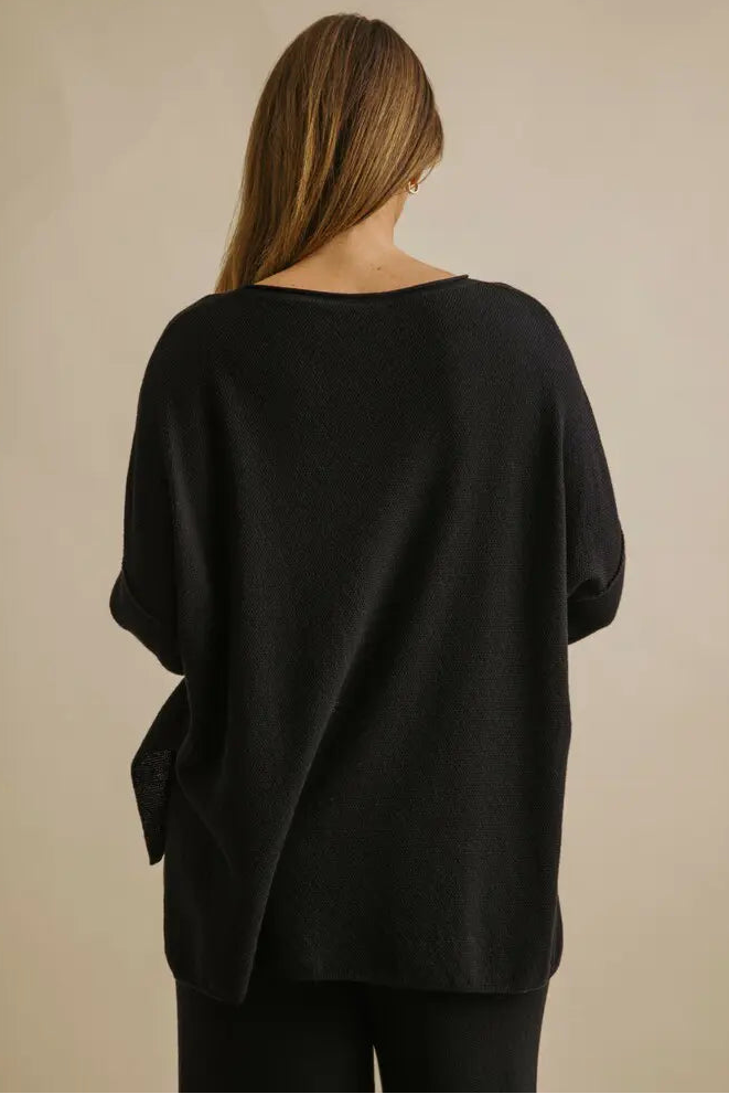 Person wearing a black sweater against a beige background